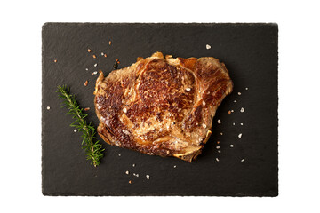 top view cooked beef steak on dark cutting board with salt and rosemary.