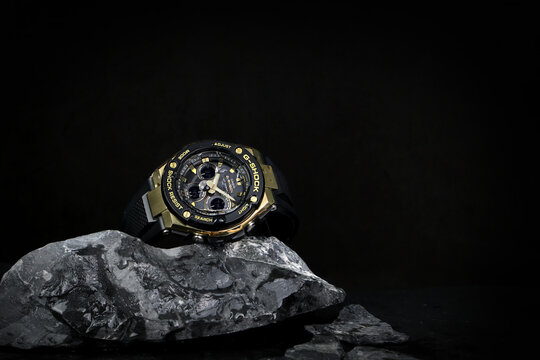 wet Casio G Shock sports durable and water resistant wrist watch is displayed on wet black stone table with stone on background of black cement wall in watches shop of  Shinjuku Japan