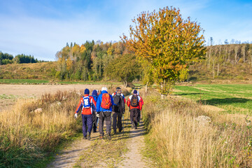 Obraz premium Group of men walking on a dirt road in a autumn landscape