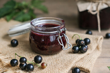 Homemade blackcurrants jam and fresh berries on a wooden background. Homemade preserving concept....