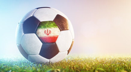 Football soccer ball with flag of Iran on grass