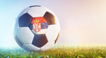 Football soccer ball with flag of Serbia on grass