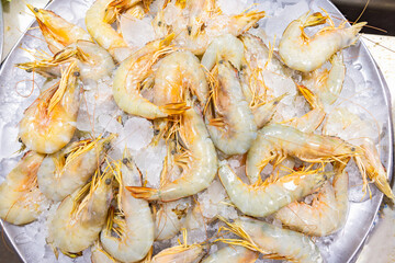 Fresh seafood such as shrimp. Big plum shrimp or white shrimp in bulk on ice in stainless steel round food tray. Display in market for sell. Top view
