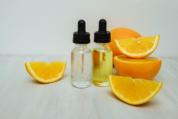 Two cosmetic bottles, glass vials with a pipette with oil and serum on a white background with slices of citrus fruits and an orange with an empty space for text, copy space, the concept of self-care