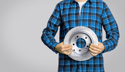 Mechanic in a blue shirt and blue jeans with car parts on a grey background