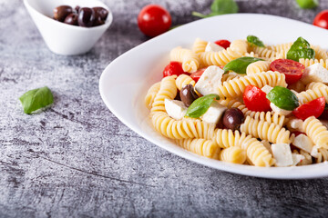 Greek-style pasta served with feta cheese, tomatoes and black olives. Typical dish of Greek and Mediterranean cuisine, suitable for a vegetarian diet.