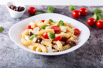 Greek-style pasta served with feta cheese, tomatoes and black olives. Typical dish of Greek and Mediterranean cuisine, suitable for a vegetarian diet.