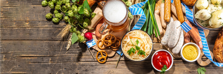 Oktoberfest holiday greeting card, menu, invitation background, Traditional Oktoberfest festival food, bavarian sausages, pretzels, potato, sauerkraut, beer mug on wooden background, banner format