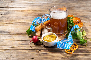Oktoberfest holiday greeting card, menu, invitation background, Traditional Oktoberfest festival food, bavarian sausages, pretzels, potato, sauerkraut, beer mug on wooden background, copy space above