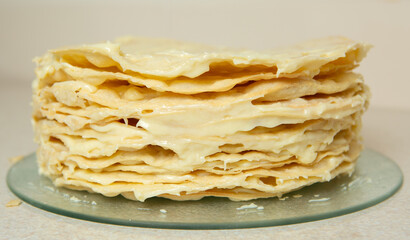 Making homemade Napoleon cake. The sides of the cake are also generously smeared with cream