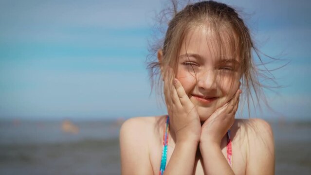 Portrait little cute child girl looking at camera standing on water in beach resort on summer day. Freedom lifestyle and traveling in holiday concept