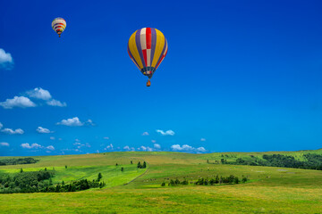 青空を背景にした地平線の見える草原と熱気球