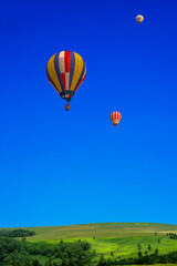 青空を背景にした地平線の見える草原と熱気球