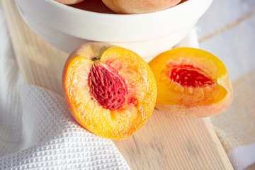 Bright fresh juicy red and orange sliced peaches on the wooden board in the sunny kitchen in summer.