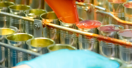 Canned fish factory. Food industry. Machine filling red tomato sauce into sardine can at food...