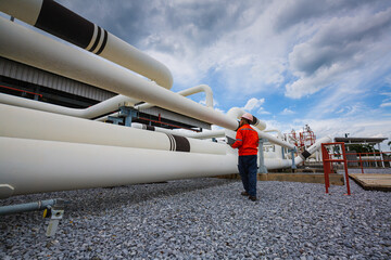 Male worker inspection at steel long pipes and pipe elbow in station oil factory during refinery valve of visual check record pipeline