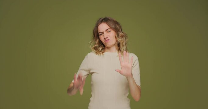 Funny female showing so-so gesture by hands on green studio background. Uncertainty, ambivalent feels concept