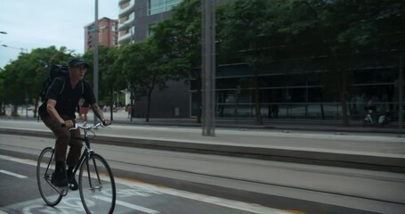 Young handsome man commute to work or school on minimalistic city bike. Student or office worker on way to university or office ride bike on bikelane
