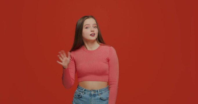 Doubtful young girl showing so-so hand gesture, doubting on orange studio background. Uncertainty, ambivalent estimate