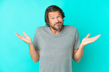 Fototapeta premium Senior dutch man isolated on blue background having doubts while raising hands