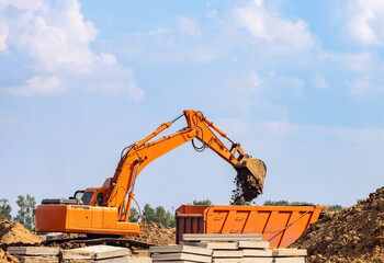 Orange color excavator loading dump truck on the construction site	