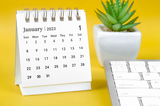 The January 2023 desk calendar and computer keyboard on yellow background.
