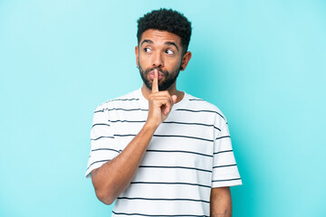 Young Brazilian man isolated on blue background showing a sign of silence gesture putting finger in mouth