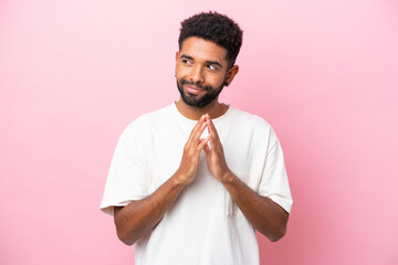 Young Brazilian man isolated on pink background scheming something