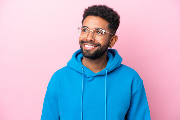 Young Brazilian man isolated on pink background With glasses with happy expression