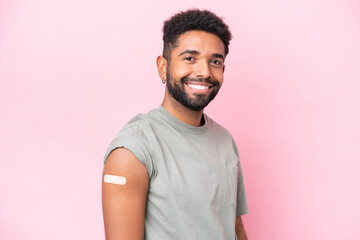 Young Brazilian man wearing a band aid isolated on pink background smiling a lot