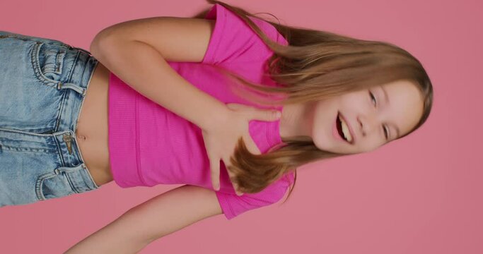 Hilarious elementary child girl hooligan laughing, teasing, having fun, pointing to camera by finger. Vertical video