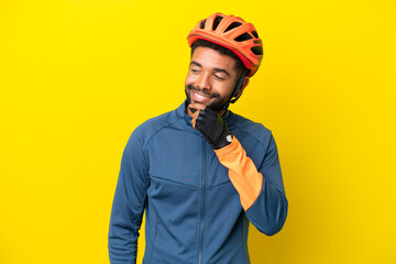 Young cyclist Brazilian man isolated on yellow background looking to the side and smiling