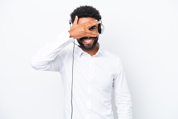 Telemarketer Brazilian man working with a headset isolated on white background covering eyes by hands and smiling