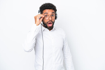 Telemarketer Brazilian man working with a headset isolated on white background with glasses and surprised