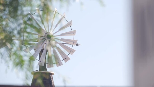 Old windmill on ranch or countryside farm, historic retro wind mill in USA. Vintage classic blade rotor for homestead. Rural provincial pump or generator turbine wheel. Wild west american symbol.