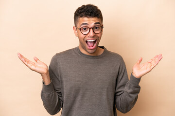 Fototapeta premium Young Brazilian man isolated on beige background with shocked facial expression