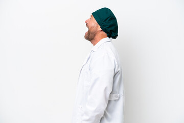 Middle age surgeon in green uniform isolated on white background laughing in lateral position