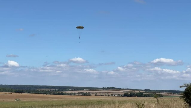 British army paratroopers (3 PARA) parachuting on an overhead assault , wearing body armour and webbing with weapons and daysacks suspended by rope below, blue sky