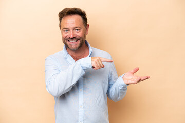 Middle age caucasian man isolated on beige background holding copyspace imaginary on the palm to...