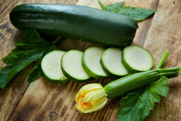 The raw product of zucchini lie on the wooden surface of the table. Ingredients for cooking. Seasonal vegetables.