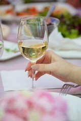 A glass of alcoholic beverage in the hands of an adult.