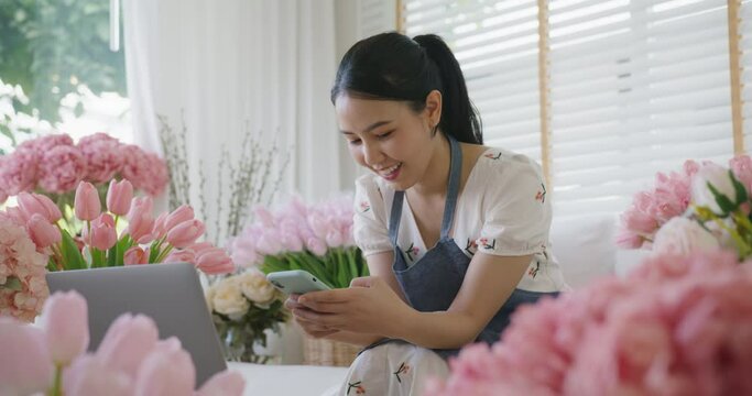 Asia Gen Z people SME owner typing chat on mobile phone app at home office retail florist store. Young girl earn loan money selling online or read text on web sale page work on social media shop.
