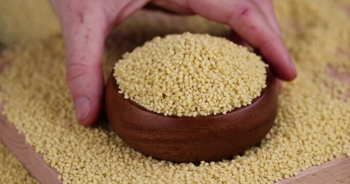 Take a bowl of raw cereal porridge couscous from wheat or millet, cooking dishes from traditional cereals crushed yellow couscous