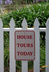 HOUSE TOURS TODAY sign mounted on a white picket fence