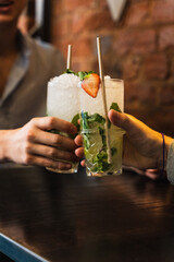 people toasting iced alcohol drink with mint and strawberry