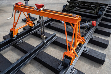Laying of railway tracks. Equipment for installing rails on sleepers. Orange cart is mounted on rails. Railway construction. Equipment for laying railroad tracks. Creating tracks for trains