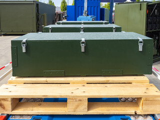 Transportation of production equipment. Closed boxes for transporting equipment. Green cases are on wooden pallets. Cases with industrial equipment in open air. Dark green cases with steel locks