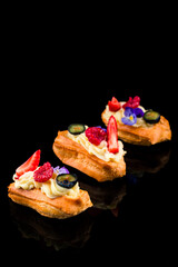 eclairs with glaze and strawberries on black