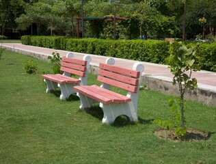 Two peach and white coloured benches in the park