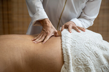 Um profissional fazendo massagem terapêutica nas costas do paciente que está deitado na maca.